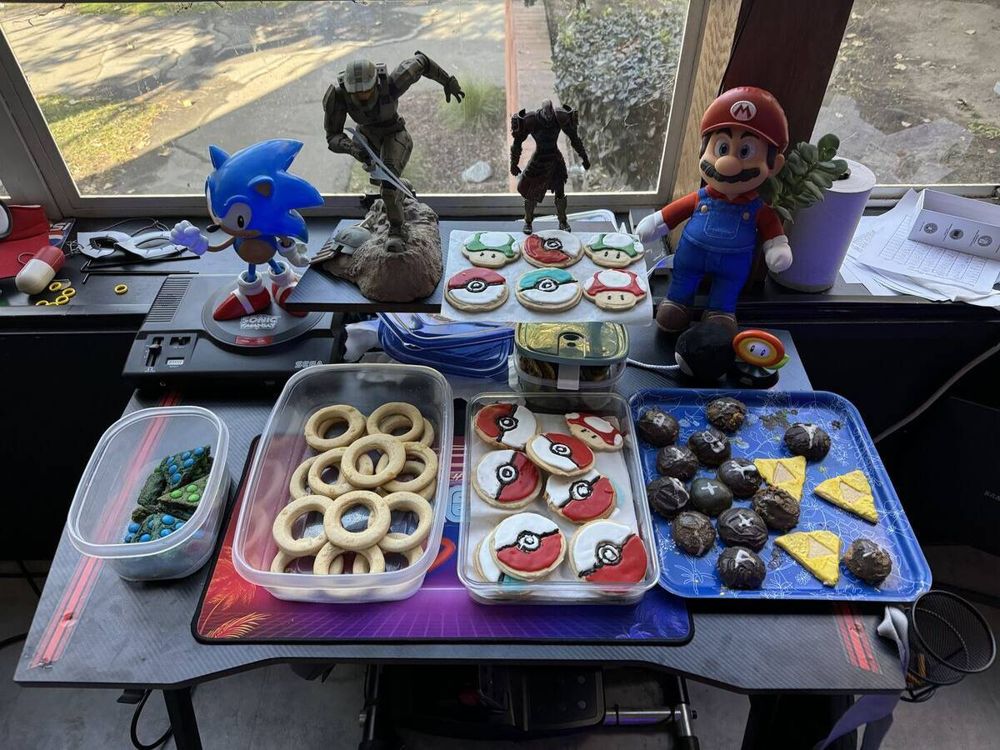 A desk of game cookies: Sonic rings, Pokeballs, Triforces, and Mario and Sonic figures behind them